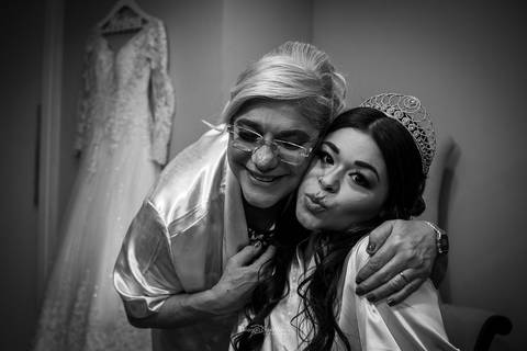 mãe abraça a noiva vestido ao fundo preto e branco '