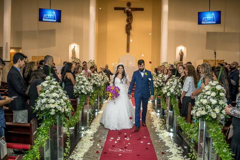 noivos saindo da igreja depois da cerimônia tapete vermelho pétalas de rosas decoração flores brancas noiva vestido buque rosa e amarelo '