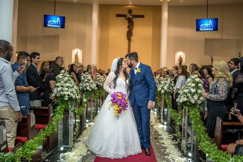 noivos se beijam saindo da igreja tapete vermelho pétalas de rosas decoração flores brancas '