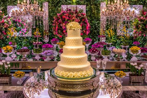 decoração parede com vegetação flores tons de rosa e amarelo lustres bolo doces '
