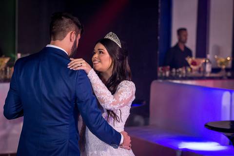 noivos dançam noiva sorri na pista bar ao fundo'
