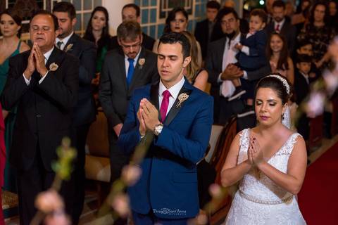 noivos fazem oração no altar junto a padrinho convidados ao fundo'