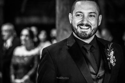 noivo sorri convidados ao fundo preto e branco'