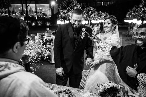 noivo sorri falando ao microfone noiva sorri no altar junto ao padre'