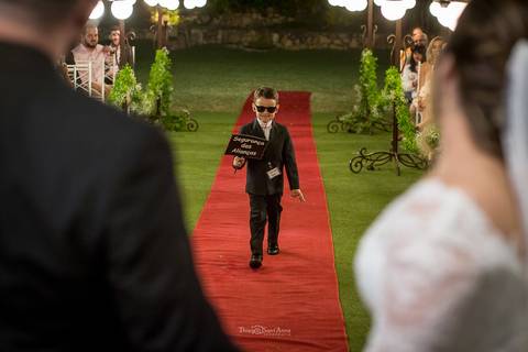 entrada do pajem com placa óculos escuros tapete vermelho vegetação '