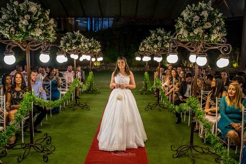 entrada dama de honra com alianças vegetação tapete vermelho postes luminárias flores brancas '