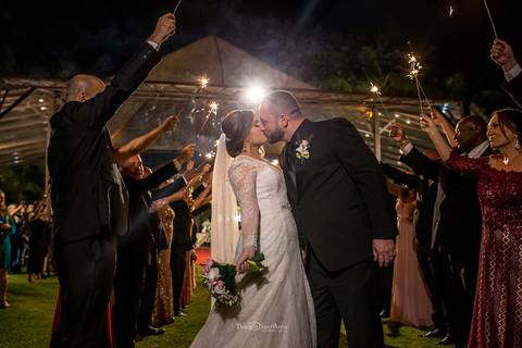 beijo dos noivos entre padrinhos levantam bastões luminosos '