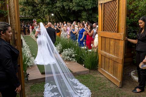 entrada da noiva seu pai vestido véu convidados observam de pé'