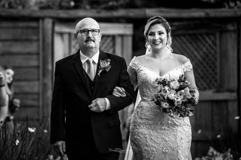 noiva sorri indo ao altar com seu pai preto e branco'