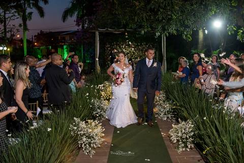 saída dos noivos convidados observam de pé vegetação flores brancas '