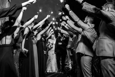 noivos passam por entre padrinhos levantam bastões luminosos preto e branco'