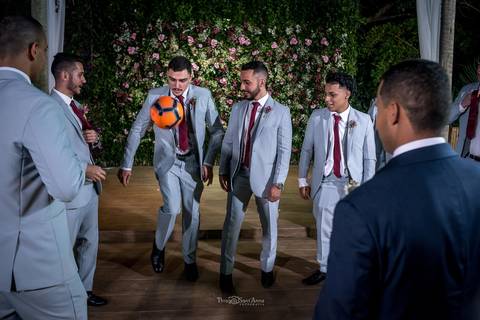 padrinhos jogam bola com noivos parede flores tons de rosa ao fundo'