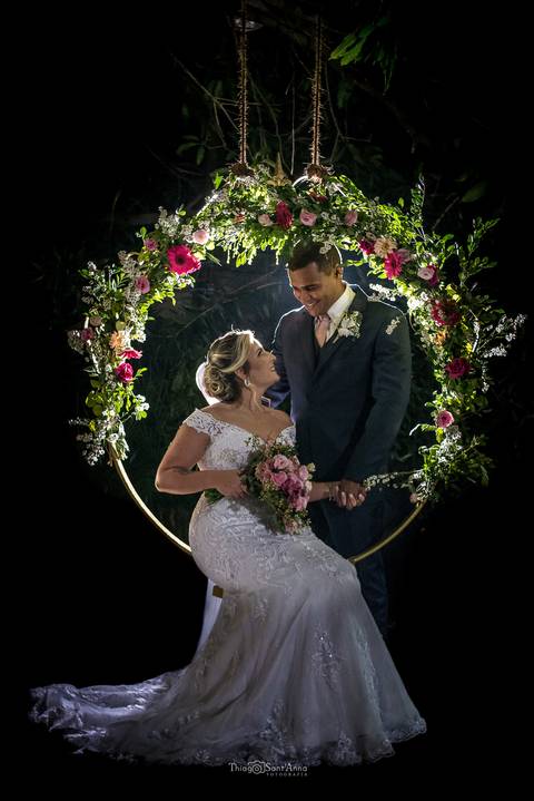 noiva vestido buque mãos dadas noivo sorri círculo dourado flores tons de rosa'