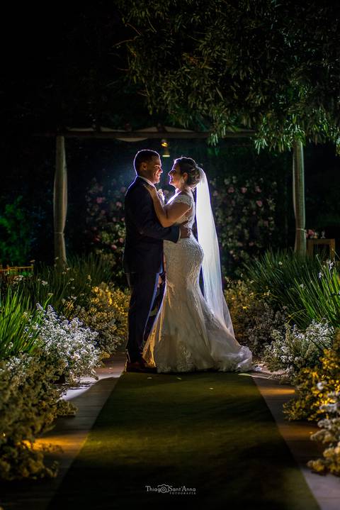 noivos se abraçam noiva vestido véu vegetação flores'