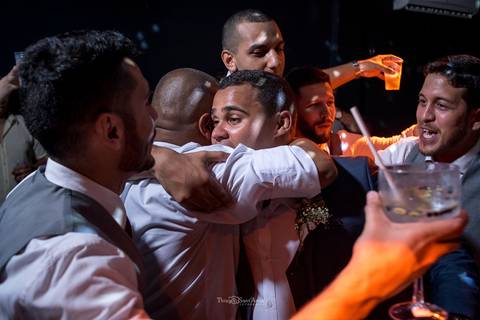 padrinho abraça o noivo convidados ao fundo'