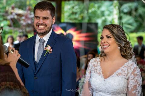noivos sorrindo no altar vegetação convidados ao fundo '