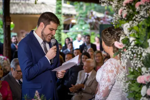 noivo lê seus votos decoração flores tons de rosa convidados ao fundo'