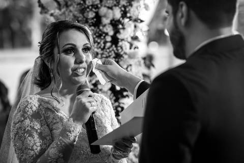 noiva sorri lendo seus votos noivo enxuga suas lágrimas preto e branco'