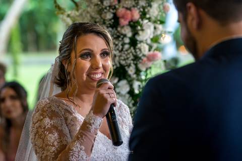 noiva sorri falando ao microfone'