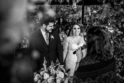 noivos no altar sorrindo decoração vegetação flores preto e branco'
