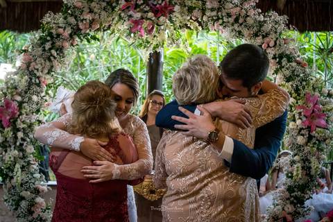 noivos abraçam suas mães no altar decoração flores tons de rosa '