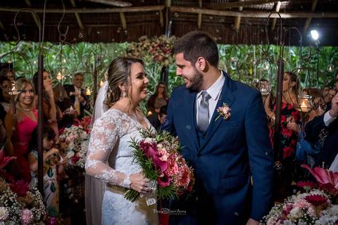 noivos sorrindo noiva buque tons de rosa convidados ao fundo'