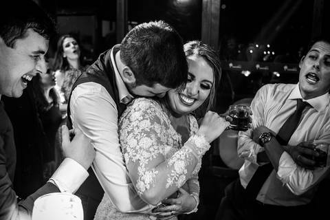 padrinho abraça madrinha sorri padrinhos ao fundo preto e branco'