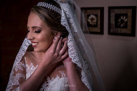 noiva sorri se preparando para o casamento vestido véu brinco'