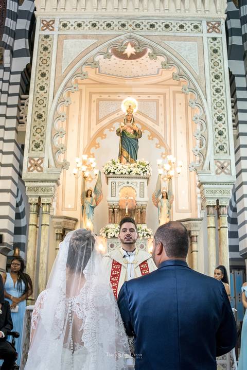 noivos no altar de frente ao padre'