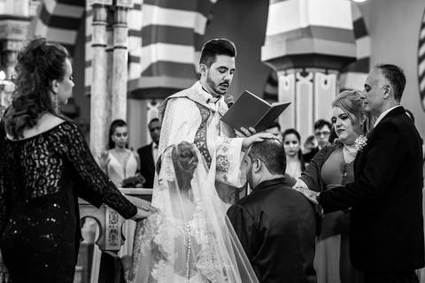 noivos recebem benção do padre preto e branco'