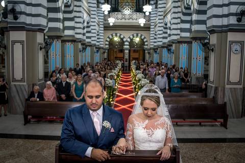 noivos rezando no altar igreja convidados ao fundo'