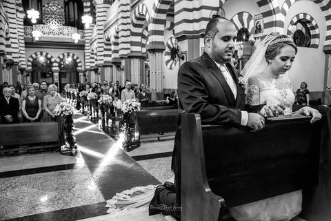 noivos rezando no altar igreja convidados ao fundo preto e branco'