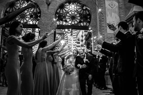 noivos passam por entre padrinhos que estendem bastões luminosos preto e branco'