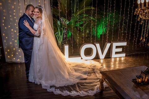 noivos se abraçam ao lado de letreiro luminoso decoração madeira lustre'