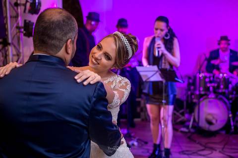 noivos dançam sorrindo de frente a banda festa casamento'