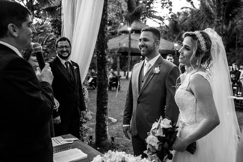 noivos no altar sorrindo junto ao pastor cerimônia casamento preto e branco '