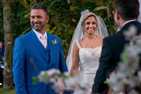 noivos sorrindo frente ao pastor vegetação ao fundo decoração flores brancas'