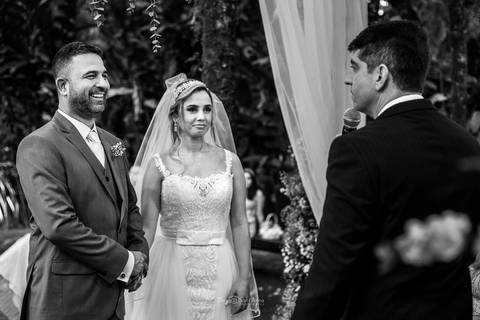 noivos no altar frente ao pastor noivo sorri preto e branco'