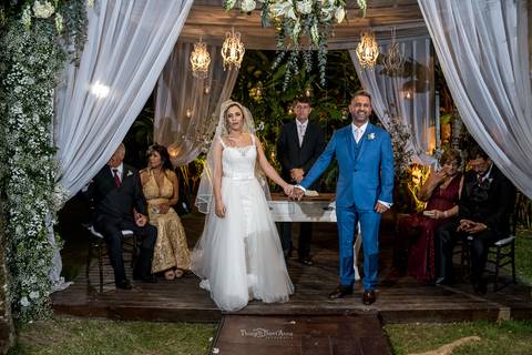 noivos de mãos dadas aguardam a chegada das damas de honra junto ao pastor e seus familiares'