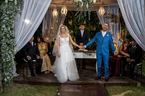 noivos de mãos dadas aguardam a chegada das damas de honra junto ao pastor e seus familiares'