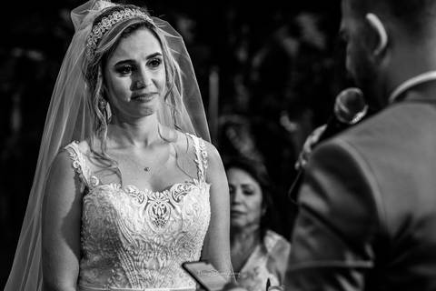 noiva emocionada ouvindo os votos do noivo preto e branco'