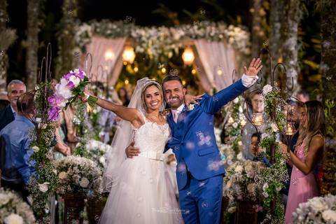 saída dos noivos posam abraçados estendem as mãos a noiva levanta o buque em tons de rosa ambiente externo decoração flores brancas '