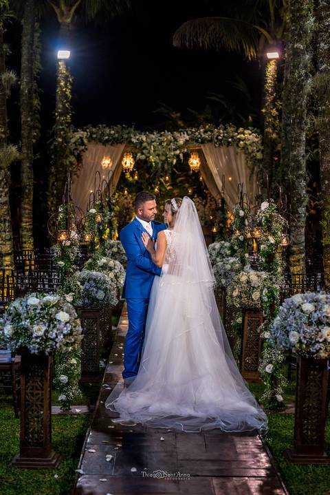 noivos abraçados noiva vestido véu noivo terno azul decoração flores brancas '