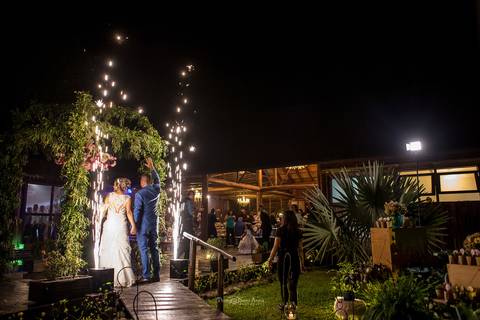 noivos entram na festa através de arco revestido por vegetação estrutura de madeira'