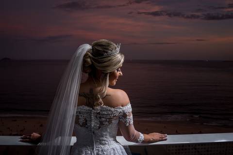 noiva de costas olha sobre o ombro vestido véu paisagem anoitecer'