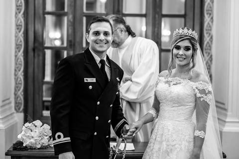 noivos sorrindo observam a entrada do pajem junto a dama de honra'