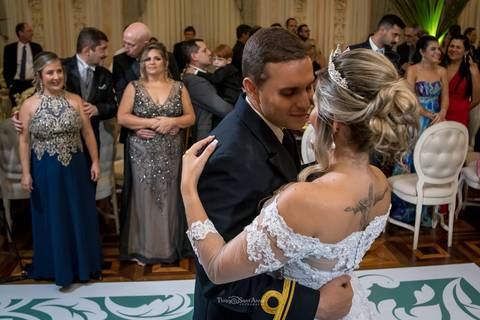 dança dos noivos padrinhos e convidados observam ao fundo'