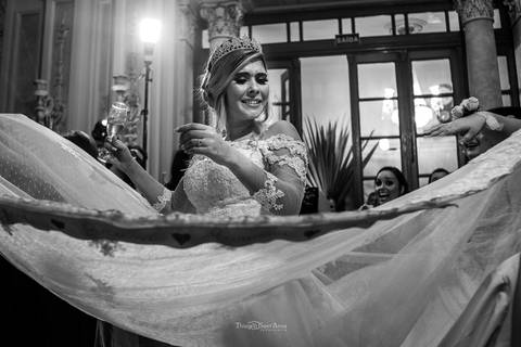 noiva sorri madrinhas em volta seguram saia de seu vestido preto e branco'