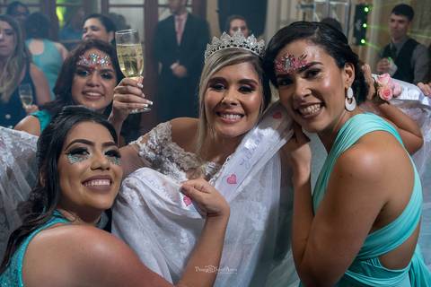 noiva sorri junto a madrinhas convidados ao fundo'