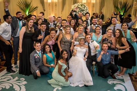 noivos posam sorrindo com convidados e padrinhos '